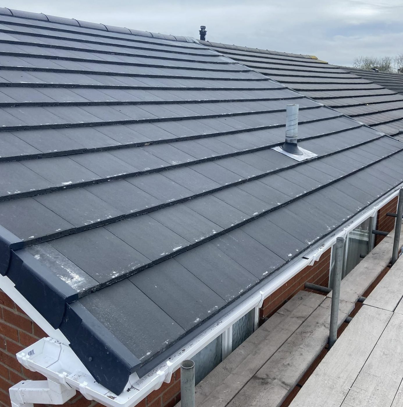 Bungalow roof re-covered in grey tiles with dry verge and white gutters