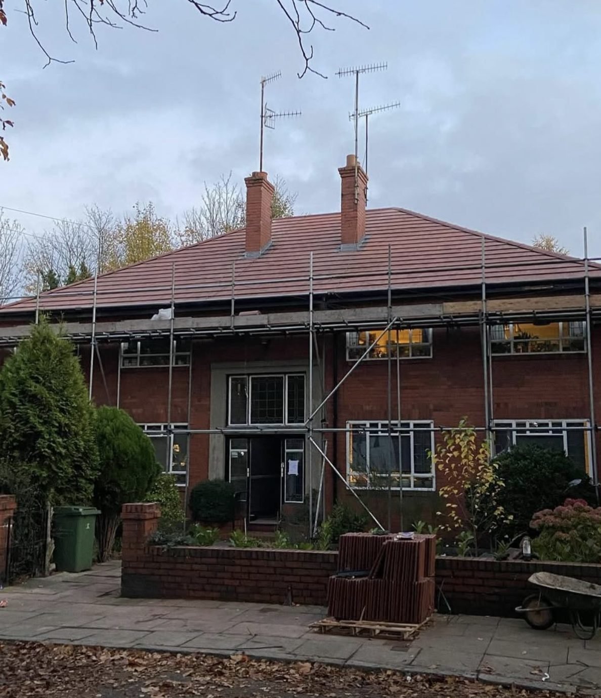 Red-brick house with a new tiled hipped roof and scaffold around it