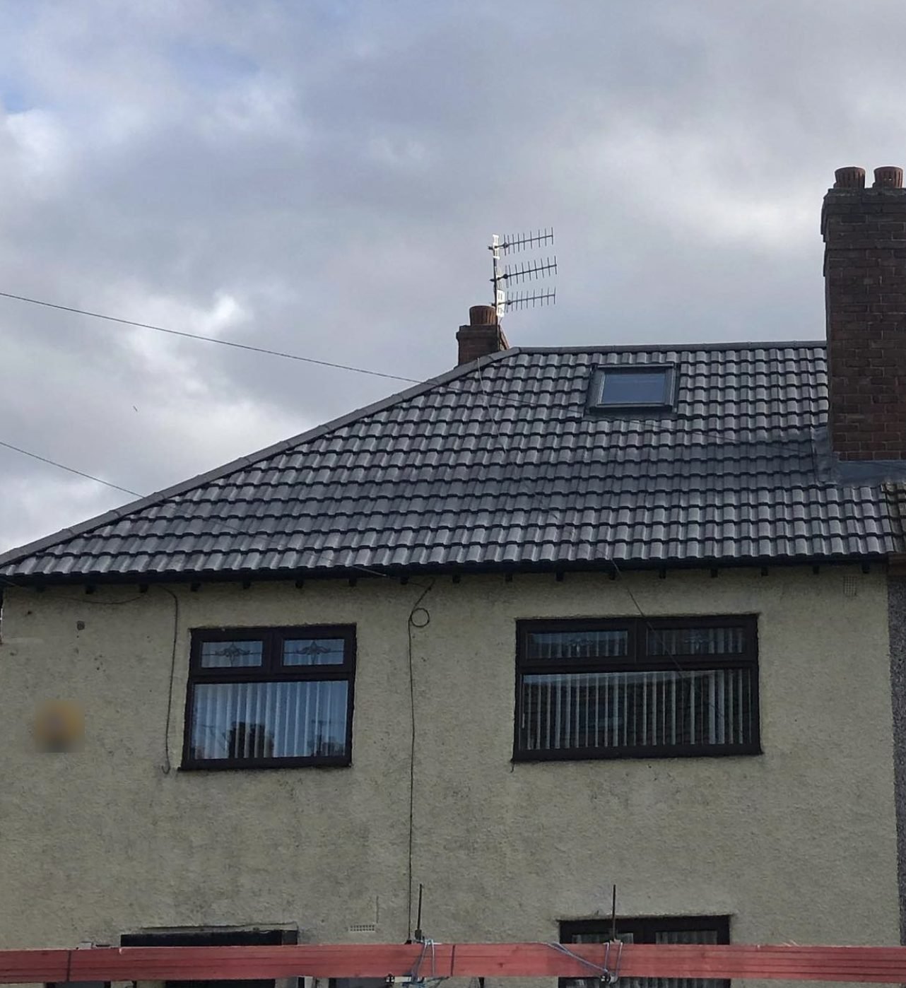 Hipped roof in dark interlocking tiles with a roof window