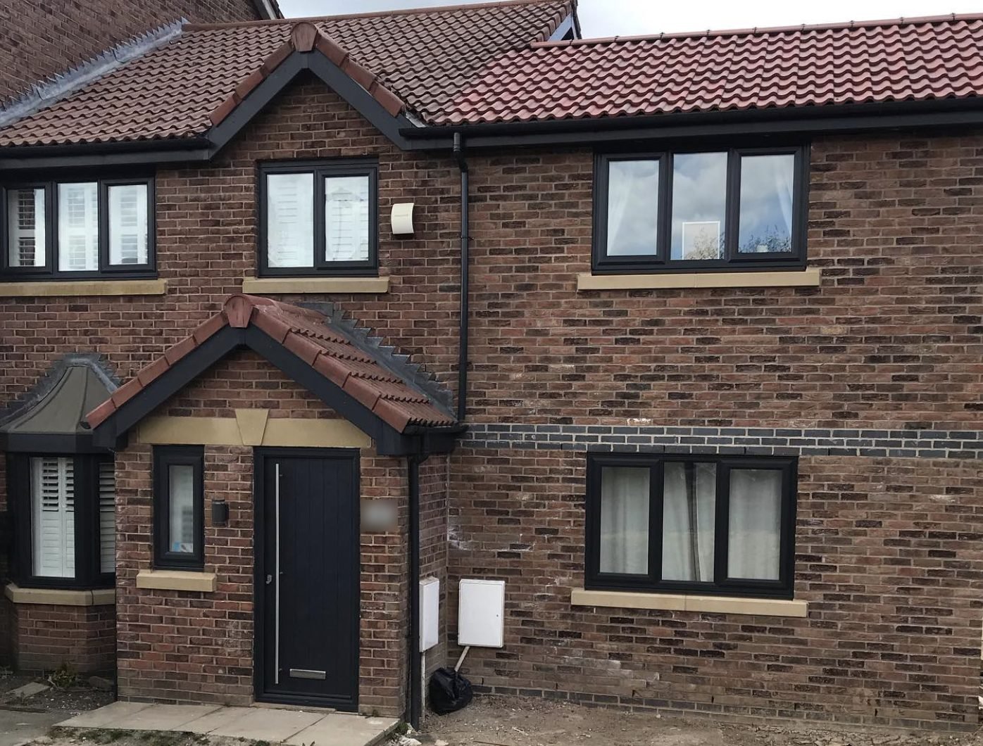 Tiled porch roof with black fascia and guttering